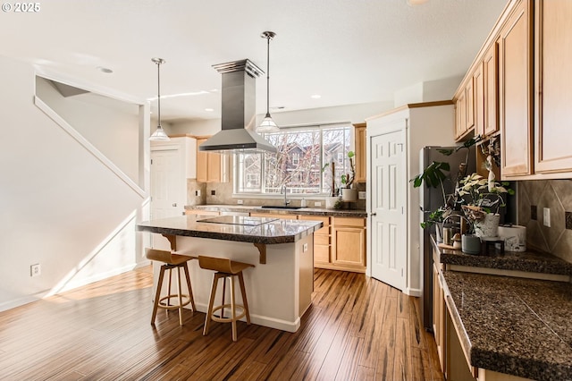 kitchen with island exhaust hood, tasteful backsplash, wood finished floors, and a sink