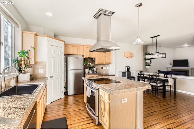 kitchen featuring light brown cabinets, island exhaust hood, a sink, stainless steel appliances, and light wood-type flooring