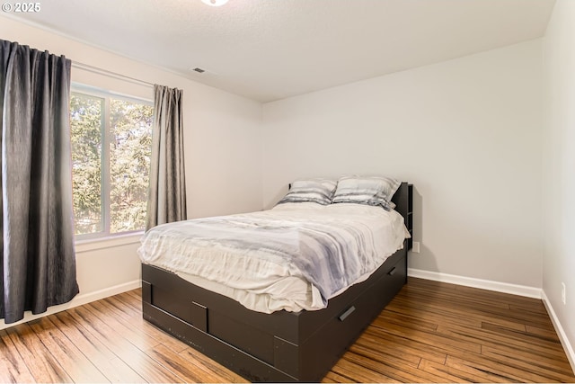 bedroom featuring visible vents, baseboards, and wood-type flooring