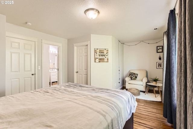 bedroom featuring visible vents, a textured ceiling, and wood finished floors