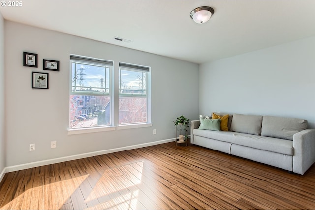 unfurnished living room featuring wood finished floors, visible vents, and baseboards