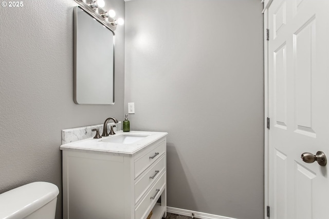 bathroom featuring vanity, toilet, and baseboards