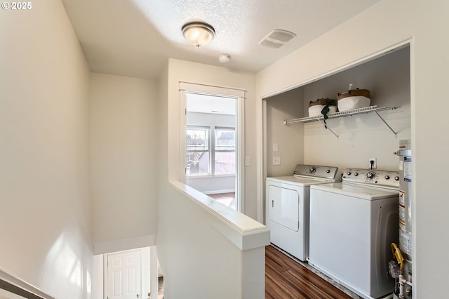 washroom featuring washer and dryer, a textured ceiling, gas water heater, laundry area, and dark wood-style flooring