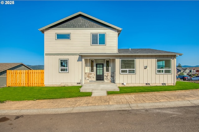 traditional-style home featuring fence, a shingled roof, a front lawn, board and batten siding, and crawl space