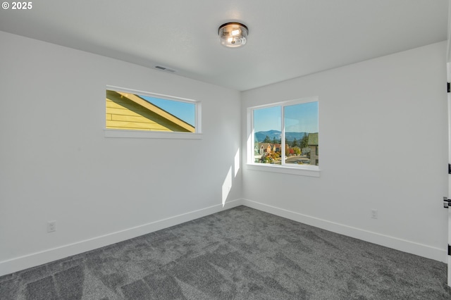 spare room with dark colored carpet, baseboards, and visible vents