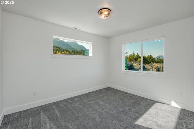 empty room with baseboards, visible vents, and dark colored carpet
