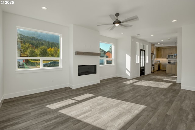 unfurnished living room featuring a ceiling fan, a glass covered fireplace, dark wood-style floors, and recessed lighting