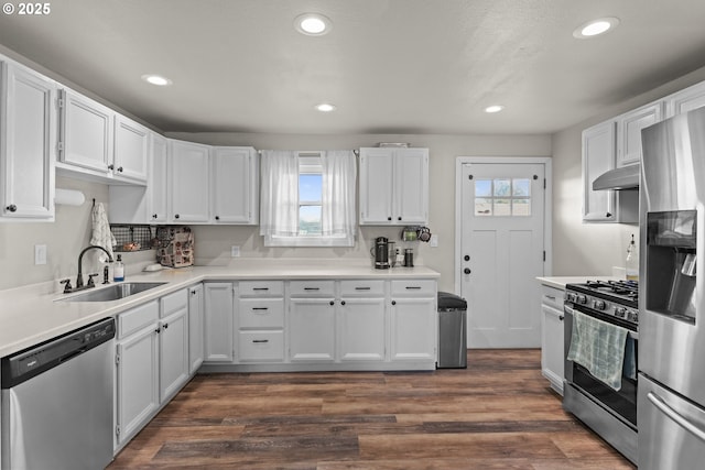 kitchen with under cabinet range hood, appliances with stainless steel finishes, white cabinets, and a sink