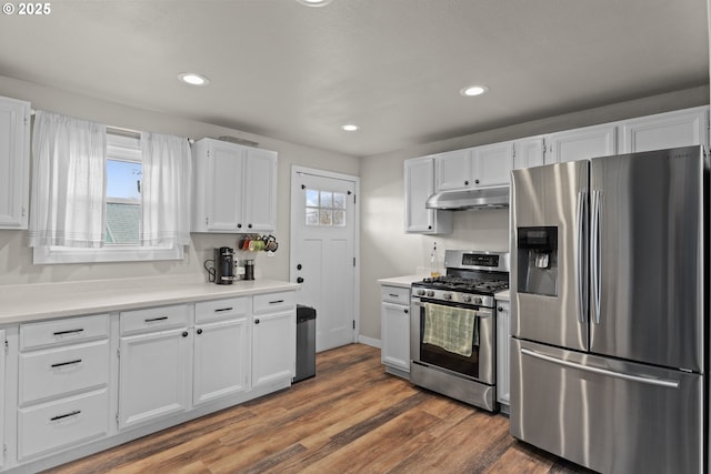 kitchen with under cabinet range hood, wood finished floors, white cabinetry, appliances with stainless steel finishes, and light countertops