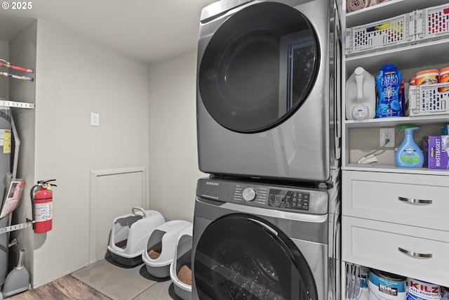 clothes washing area with cabinet space and stacked washing maching and dryer