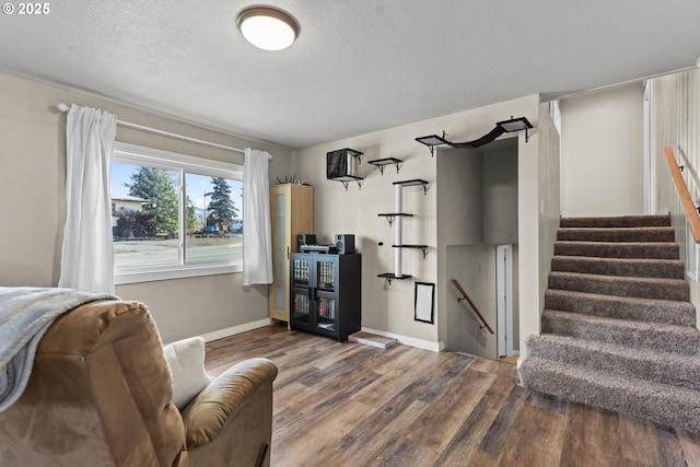 interior space with stairway, baseboards, a textured ceiling, and wood finished floors