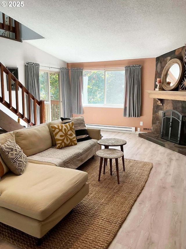 14922 SW 109th Ave, Portland, OR 97224 - living area with wood finished floors, a textured ceiling, a baseboard radiator, a stone fireplace, and lofted ceiling