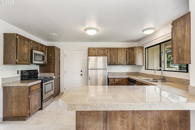12370 SW 121st Ave, Tigard, OR 97223 - kitchen with stainless steel appliances, a peninsula, a sink, tile counters, and light tile patterned floors
