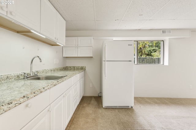 12370 SW 121st Ave, Tigard, OR 97223 - kitchen featuring freestanding refrigerator, light colored carpet, a drop ceiling, a sink, and white cabinets