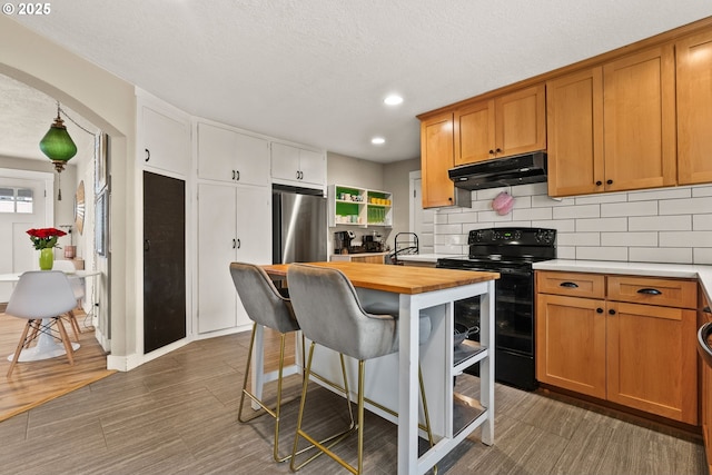 kitchen with butcher block counters, black electric range oven, decorative backsplash, and fridge