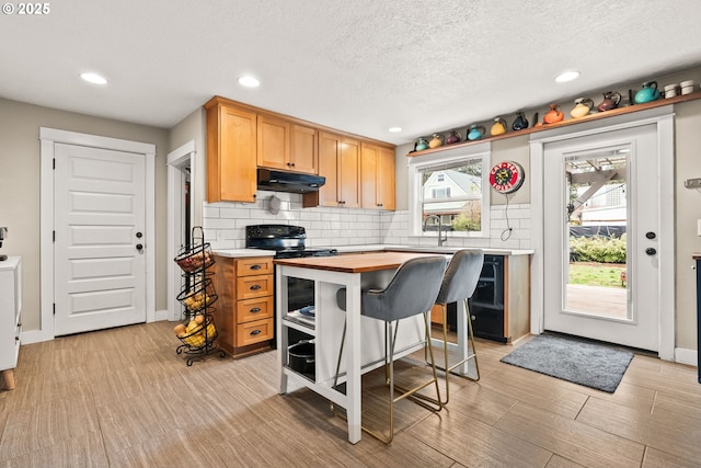 kitchen with tasteful backsplash, a kitchen island, sink, and stainless steel range with electric stovetop