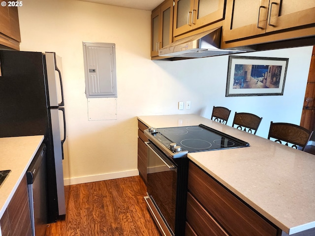 kitchen with black / electric stove, under cabinet range hood, light countertops, electric panel, and dark wood finished floors