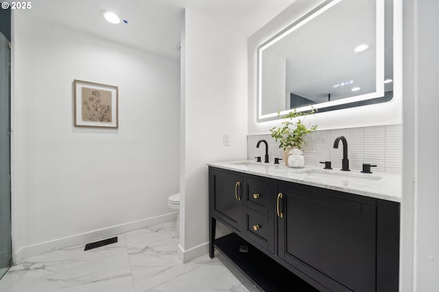 bathroom with vanity, toilet, and decorative backsplash