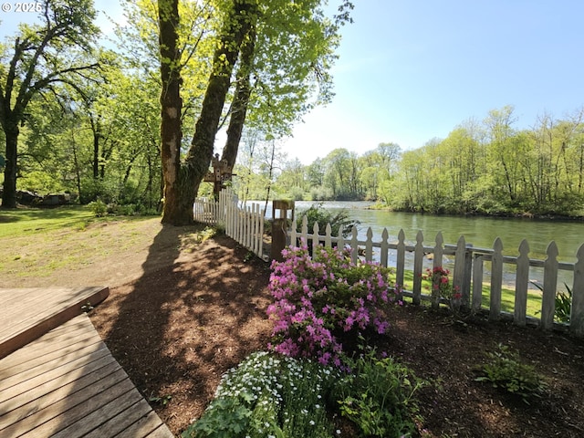 view of yard with a water view, fence, and a wooded view