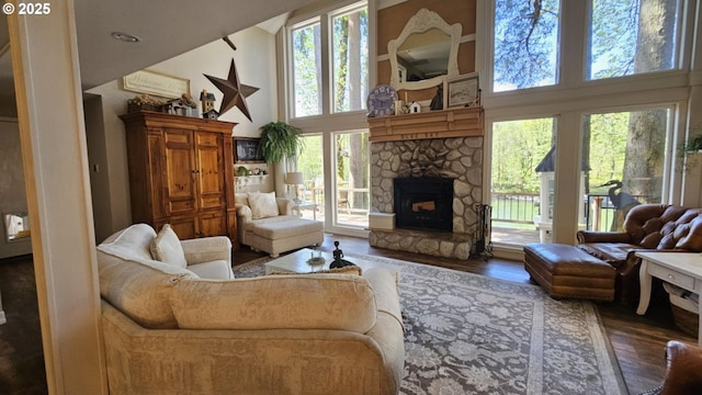 living room featuring a high ceiling, wood finished floors, and a stone fireplace