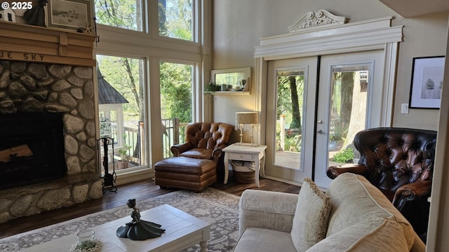 living room with plenty of natural light, wood finished floors, a fireplace, and a towering ceiling