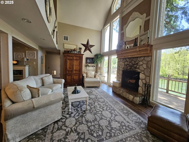 living area with a fireplace, high vaulted ceiling, and wood finished floors