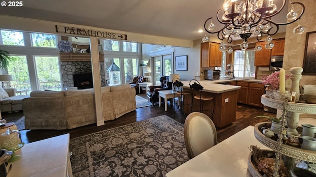 kitchen with open floor plan, a chandelier, a peninsula, brown cabinetry, and light countertops
