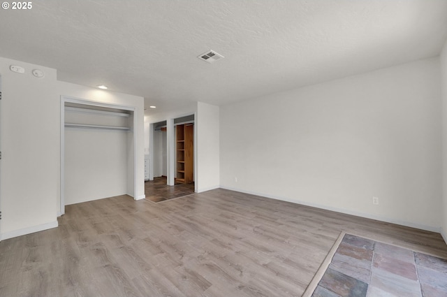 unfurnished bedroom featuring wood finished floors, baseboards, a textured ceiling, and recessed lighting