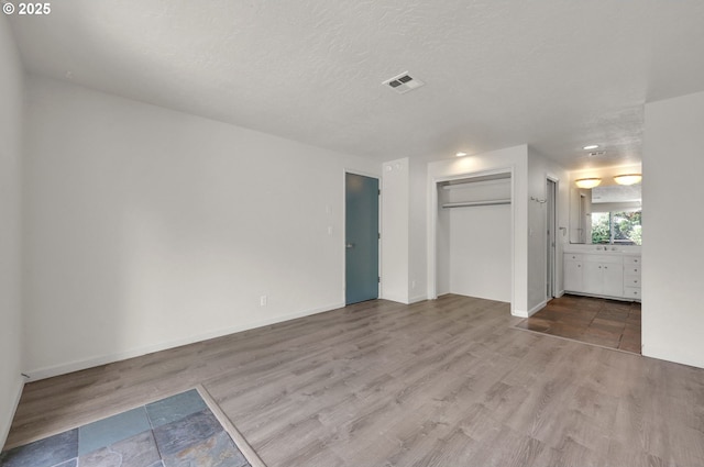 unfurnished living room with wood finished floors, baseboards, and a textured ceiling