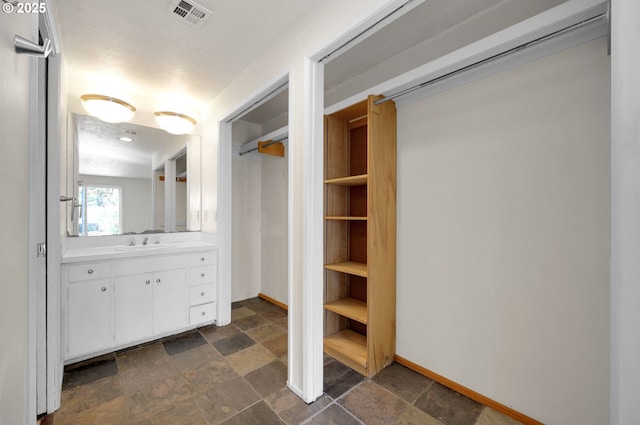 bathroom with stone finish floors, baseboards, and vanity