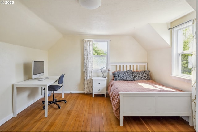 bedroom featuring lofted ceiling, wood-type flooring, an office area, and baseboards