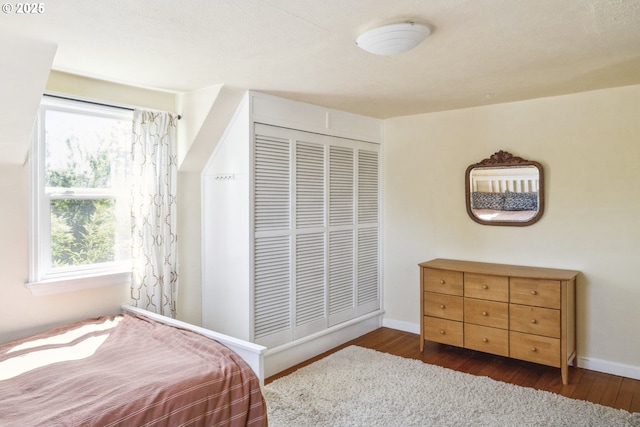 bedroom with wood finished floors, a closet, and baseboards