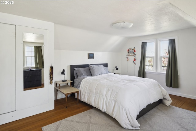 bedroom featuring wood finished floors, multiple windows, and vaulted ceiling