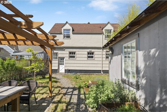 rear view of house featuring a pergola, outdoor dining space, fence, and stucco siding