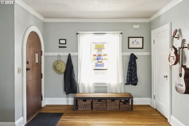 mudroom featuring wood finished floors, a textured ceiling, crown molding, and baseboards