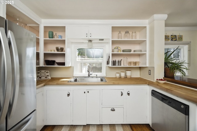 kitchen with appliances with stainless steel finishes, a sink, open shelves, and white cabinets