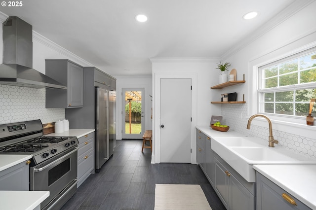 3321 NE 13th Ave, Portland, OR 97212 - kitchen featuring stainless steel appliances, gray cabinetry, wall chimney exhaust hood, crown molding, and tasteful backsplash