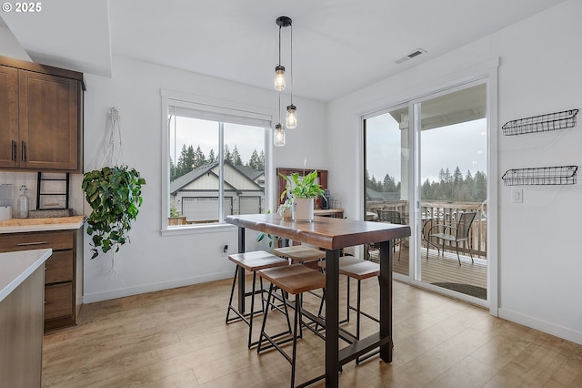 dining area with light wood-style flooring, visible vents, and baseboards