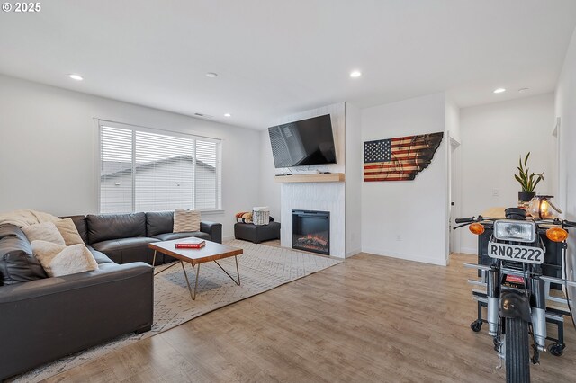 living area with a large fireplace, baseboards, wood finished floors, and recessed lighting