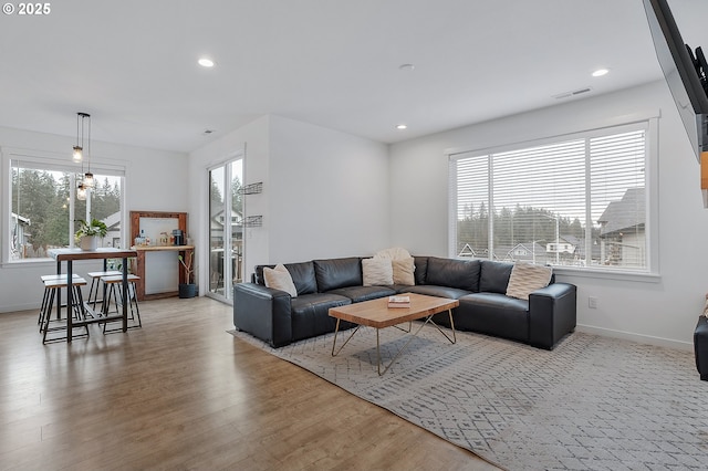 living area with baseboards, light wood-type flooring, visible vents, and recessed lighting