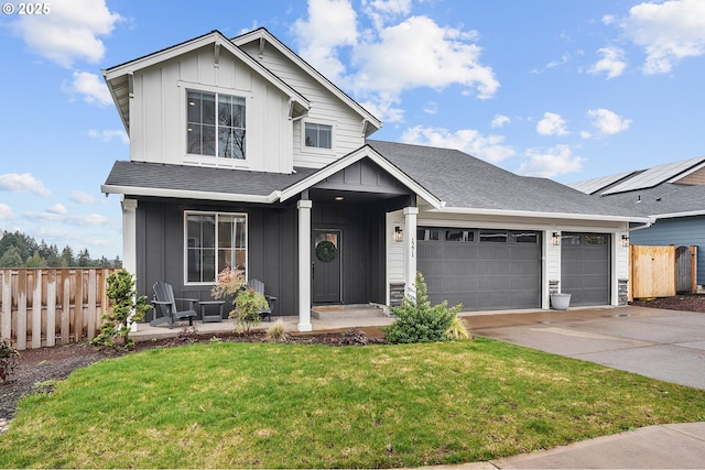 view of front of property featuring board and batten siding, a front lawn, fence, and a garage