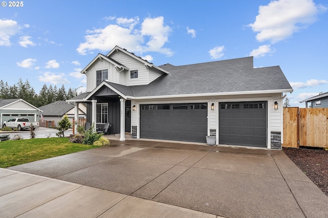 view of front facade with driveway, stone siding, an attached garage, fence, and board and batten siding