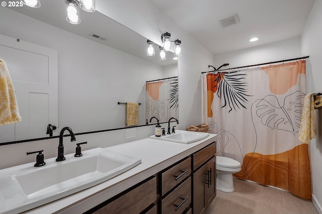 bathroom with toilet, a sink, and visible vents