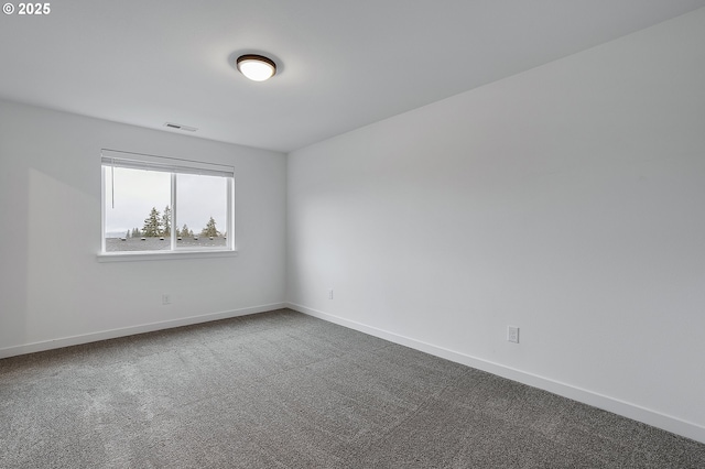 unfurnished room with baseboards, visible vents, and dark colored carpet