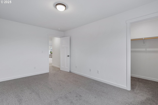 unfurnished bedroom featuring a spacious closet, carpet, and baseboards