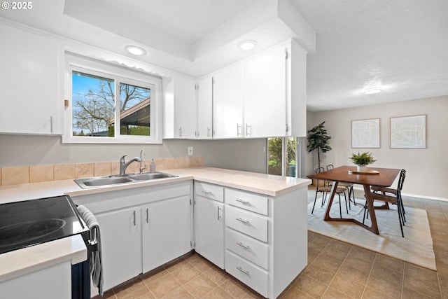 kitchen featuring a sink, a textured ceiling, recessed lighting, white cabinets, and light countertops