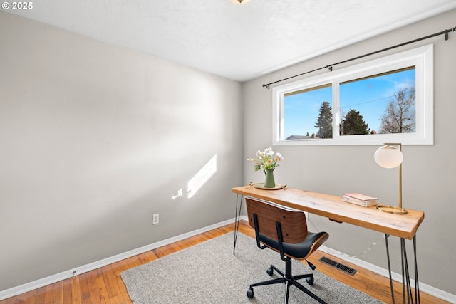 home office with visible vents, baseboards, and wood finished floors