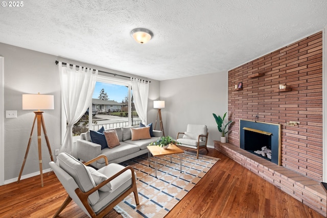 living room featuring a brick fireplace, baseboards, and wood finished floors