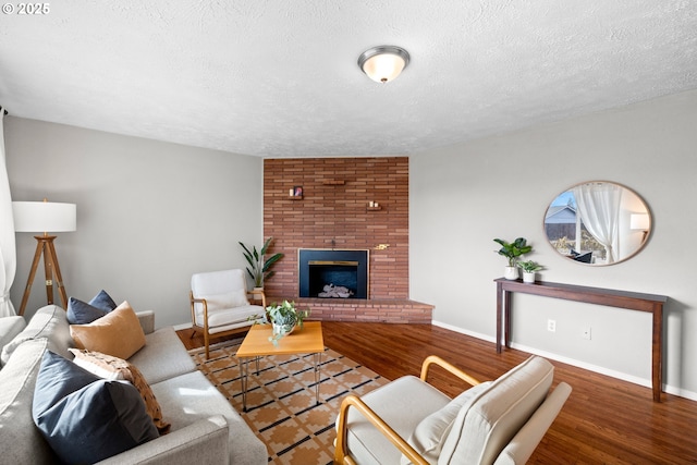 living area with a brick fireplace, baseboards, and wood finished floors