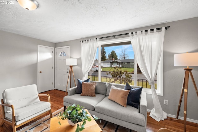 living area with wood finished floors, baseboards, and a textured ceiling